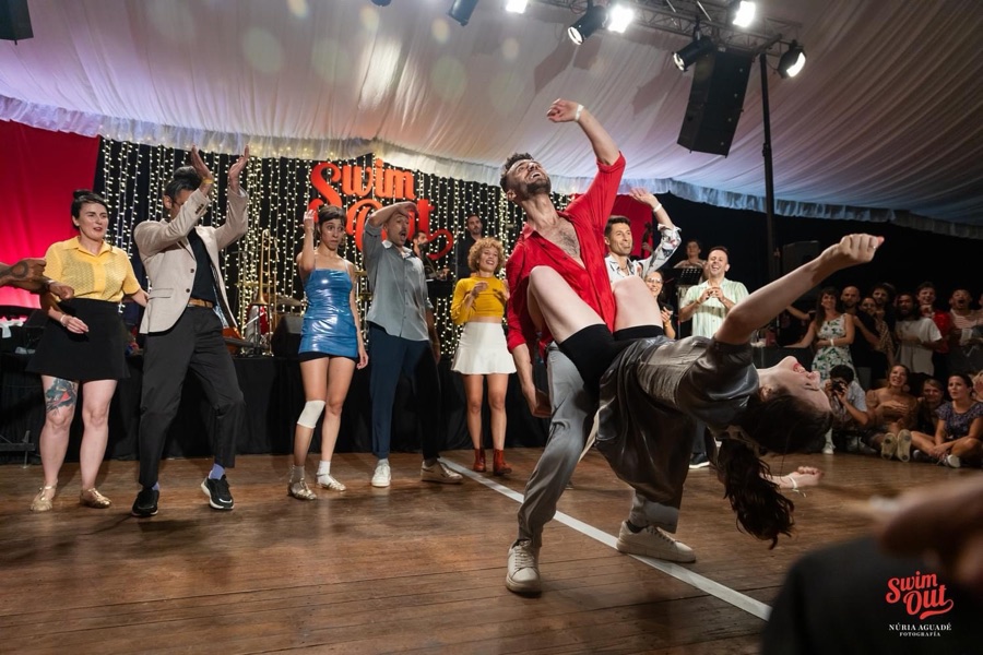 Ionuț Băjescu dancing Lindy Hop on stage at the Swim Out festival, dipping his partner during a performance